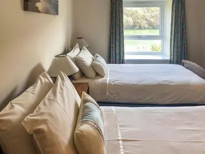 a bedroom with two beds and a couch and a window at Riverside in Truro
