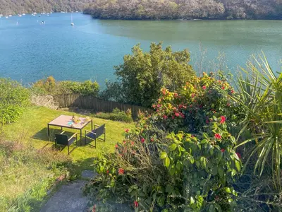 a picnic table in the grass next to a lake at Riverside in Truro