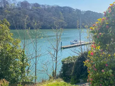 a dock on a lake with a boat in the water at Riverside in Truro