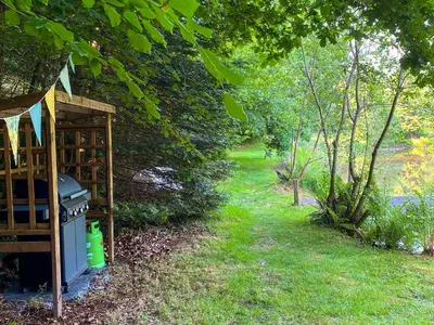 a backyard with a stove and a path with trees at The Goose Nest in Cardinham