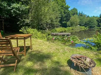 a picnic table and bench in the grass next to a pond at The Goose Nest in Cardinham
