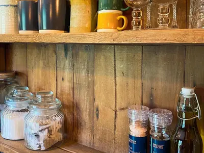 a wooden shelf with jars and other items on it at The Goose Nest in Cardinham