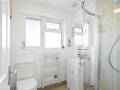 a white bathroom with a shower and a toilet at Liwus in Newquay