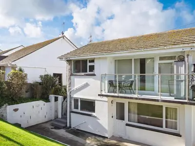 a white house with a balcony at Liwus in Newquay
