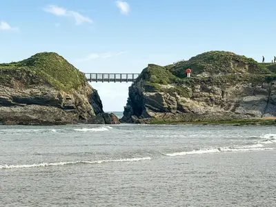 a bridge on top of a cliff next to the ocean at Liwus in Newquay