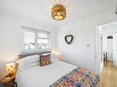 a white bedroom with a bed and a mirror at Liwus in Newquay