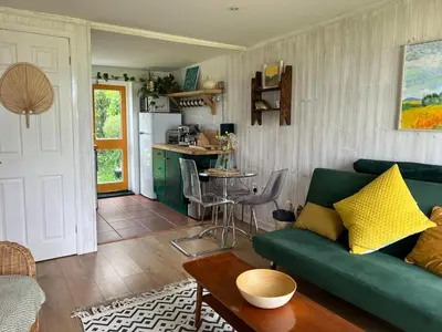 a living room with a green couch and a kitchen at Cassajossy in Bude
