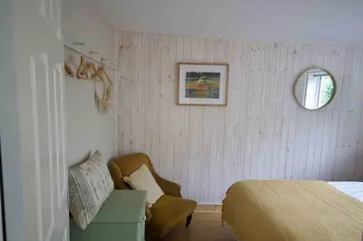 a bedroom with a bed and a chair and a mirror at Cassajossy in Bude