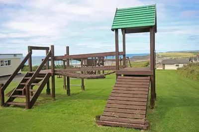 a wooden play structure with a green roof at Cassajossy in Bude