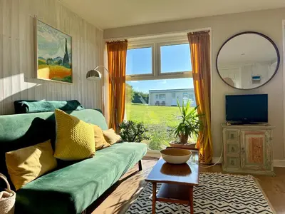a living room with a green couch and a mirror at Cassajossy in Bude