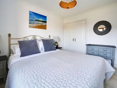 a bedroom with a white bed with blue pillows at Wenlock in Polzeath