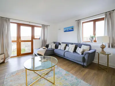 a living room with a blue couch and a glass table at Wenlock in Polzeath