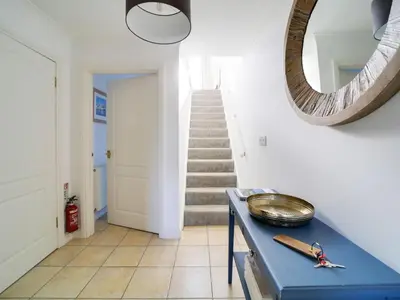 a hallway with a blue table and a mirror at Wenlock in Polzeath