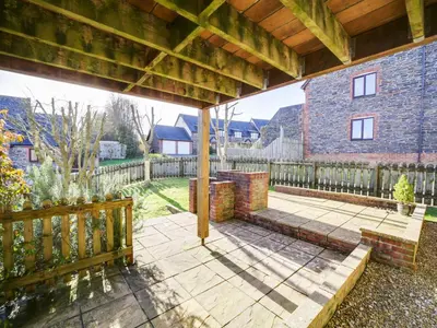 a patio with a wooden fence and a brick building at Wenlock in Polzeath