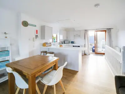 a kitchen and dining room with a wooden table and chairs at Wenlock in Polzeath