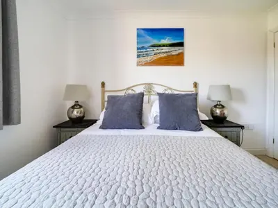 a bedroom with a large white bed with blue pillows at Wenlock in Polzeath