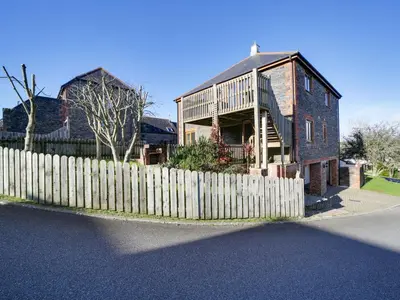 a brick house with a wooden fence in front of it at Wenlock in Polzeath