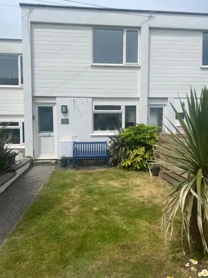 a house with a blue bench in the yard at Stunning Sea View Apartment in Newquay with 2 Heated Pools in Crantock