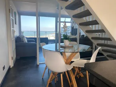 a dining room with a table and chairs with a view of the ocean at Stunning Sea View Apartment in Newquay with 2 Heated Pools in Crantock