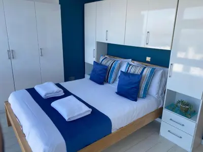a bedroom with a large bed with blue walls and white cabinets at Stunning Sea View Apartment in Newquay with 2 Heated Pools in Crantock