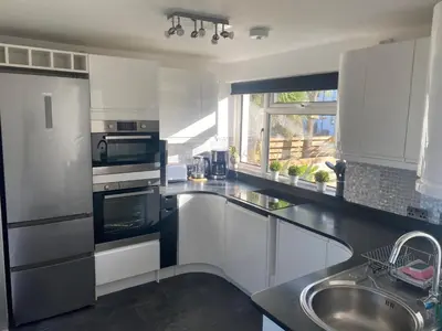 a kitchen with black and white appliances and a sink at Stunning Sea View Apartment in Newquay with 2 Heated Pools in Crantock
