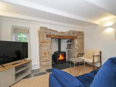 a living room with a blue couch and a fireplace at Sunrise Cottage in Bodmin
