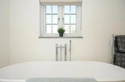 a bath tub in a white bathroom with a window at Sunrise Cottage in Bodmin