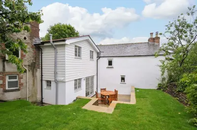 a white house with a wooden table in the yard at Sunrise Cottage in Bodmin