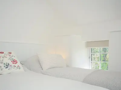a white bedroom with a bed and a window at Sunrise Cottage in Bodmin