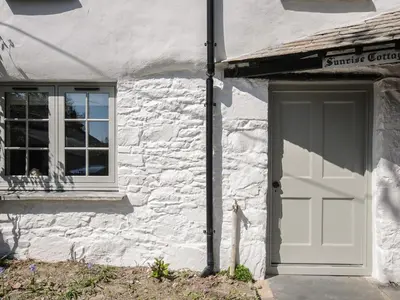 a white building with a door and a window at Sunrise Cottage in Bodmin