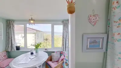 a dining room with a table and a window at B18 Sandford, Riviere Towans in Hayle