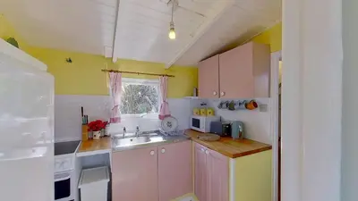 a small kitchen with white cabinets and a sink at B18 Sandford, Riviere Towans in Hayle