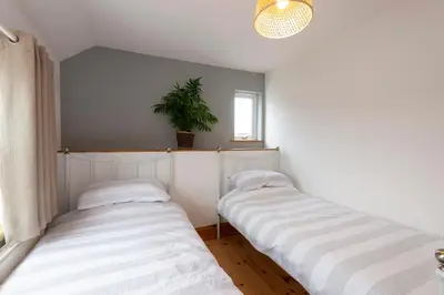 two beds in a room with a potted plant at Stylish Cottage - Walk to Beach & Pubs & Fast WiFi in St. Agnes