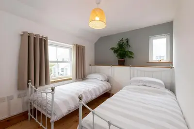 two beds in a small room with a window at Stylish Cottage - Walk to Beach & Pubs & Fast WiFi in St. Agnes