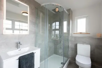 a bathroom with a shower and a toilet and a sink at Stylish Cottage - Walk to Beach & Pubs & Fast WiFi in St. Agnes