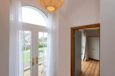an arched window in a room with a door at Stylish Cottage - Walk to Beach & Pubs & Fast WiFi in St. Agnes