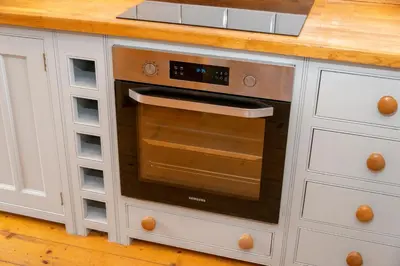 a kitchen with white cabinets and an oven at Stylish Cottage - Walk to Beach & Pubs & Fast WiFi in St. Agnes