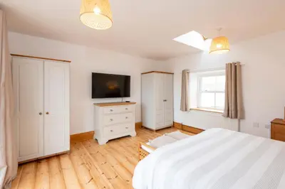 a bedroom with a bed and a flat screen tv at Stylish Cottage - Walk to Beach & Pubs & Fast WiFi in St. Agnes