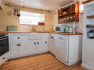 a kitchen with white cabinets and a window at Teana Cottage in Looe