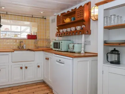a kitchen with white cabinets and a microwave at Teana Cottage in Looe