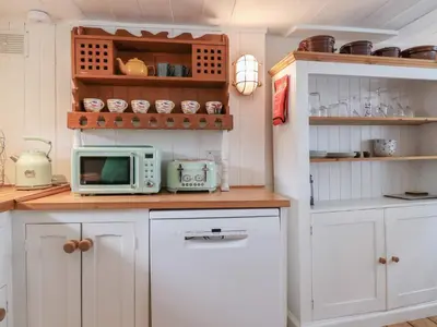 a kitchen with white cabinets and a microwave at Teana Cottage in Looe