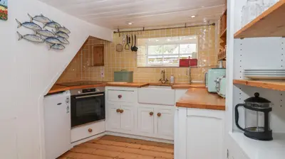 a kitchen with white cabinets and a sink at Teana Cottage in Looe