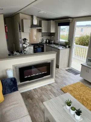 a living room with a fireplace and a kitchen at Sea Breeze Escape in Cubert