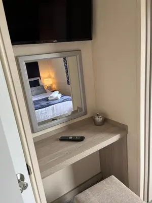 a bedroom with a mirror and a remote control on a shelf at Sea Breeze Escape in Cubert