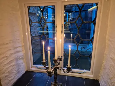 a candle holder with two candles in front of a window at OXOX - Room Only Accommodation in Polperro