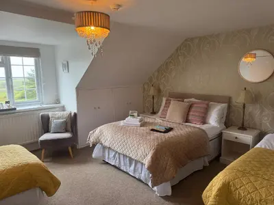 a bedroom with a bed and a chair and a chandelier at The Balnoon Inn B&B in St Ives