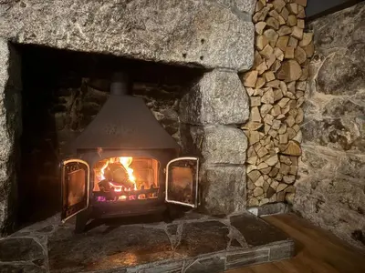 a stone fireplace with a fire in it at The Balnoon Inn B&B in St Ives