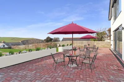a patio with tables and chairs and an umbrella at Keynvor View in Port Isaac