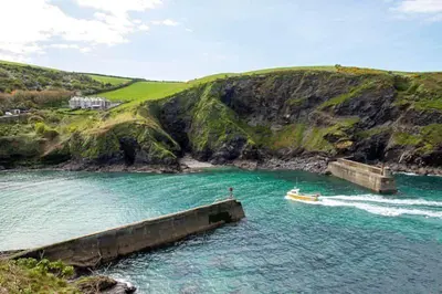a boat in the water next to a pier at Seaspray in Port Isaac