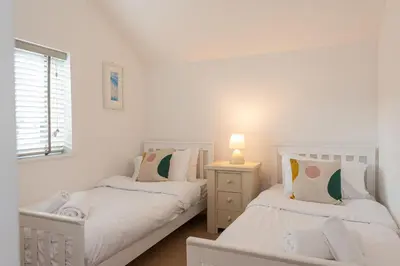 two white beds in a room with a window at Seaspray in Port Isaac